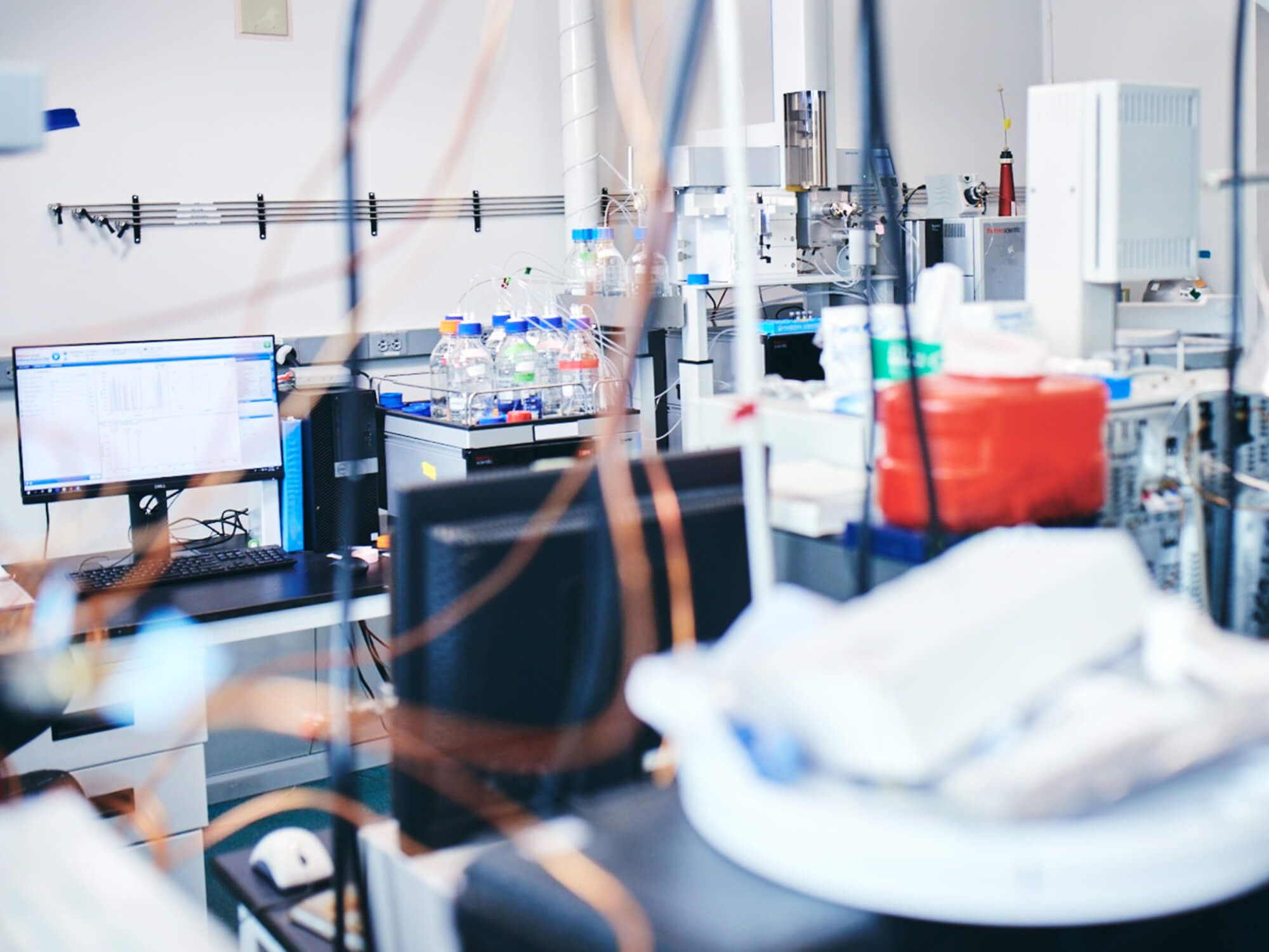 Analytical laboratory seen through a glass wall, with instruments and a workstation