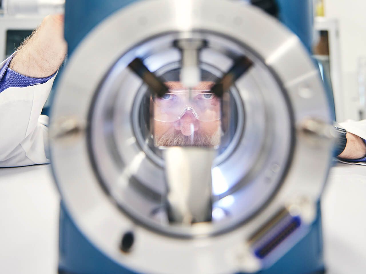 Close-up of the ion source of a mass spectrometer, with a technician looking through the viewing window
