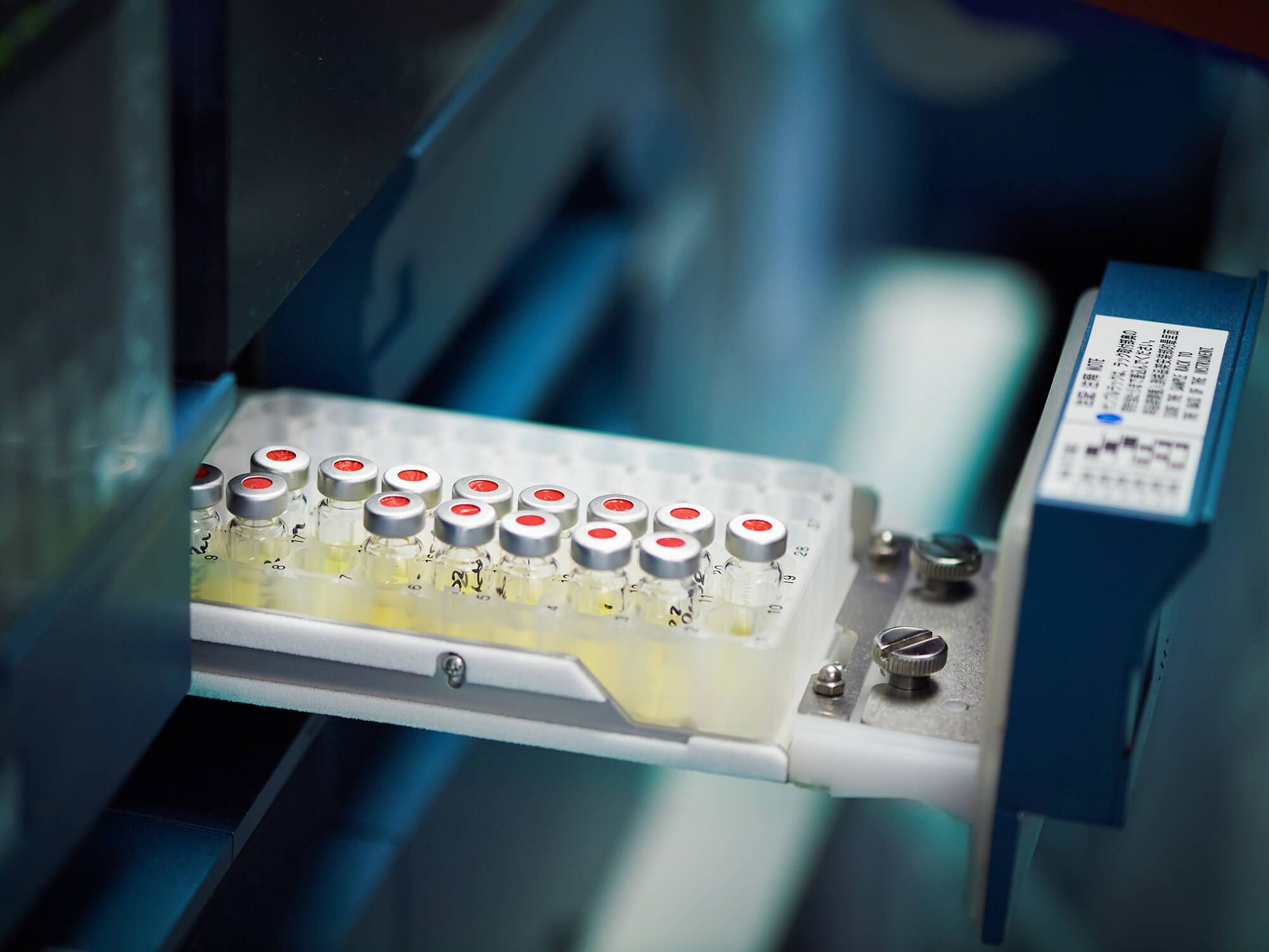 Vial with a red cap in the autosampler tray, in warm light